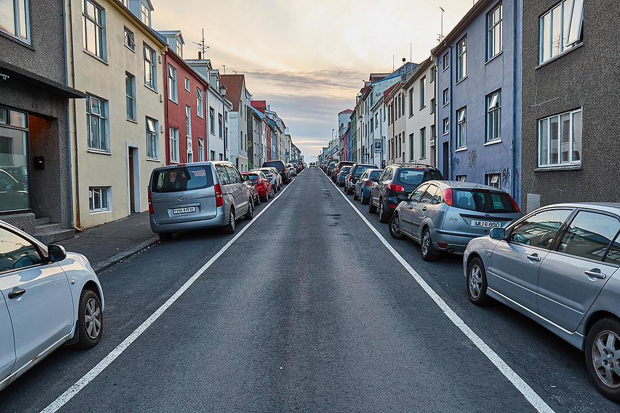 An urban street in Reykjavík, with cars parked by the sidewalk surrounding buildings on either side
